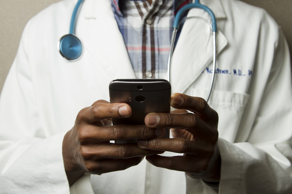 A clinician in a white coat using a phone between duties.