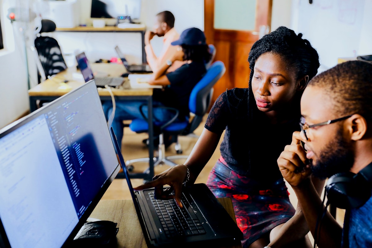 Colleagues in discussion at a laptop during a staff process.